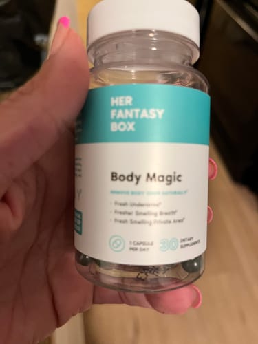 Reviewer holding a clear bottle of Body Magic chlorophyll pills.