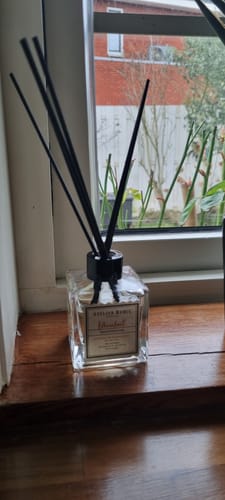 Recensent toont de Istanbul Huisparfum met geurstokjes in de fles op een houten vensterbank.