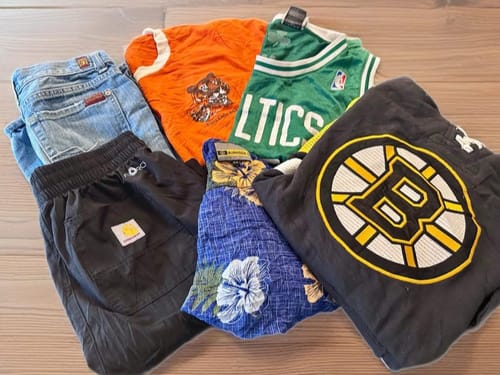 Reviewer's haul from the Kids Vintage & Retro Mix, showing a variety of shirts, shorts, jeans, a jersey, and a hoodie.