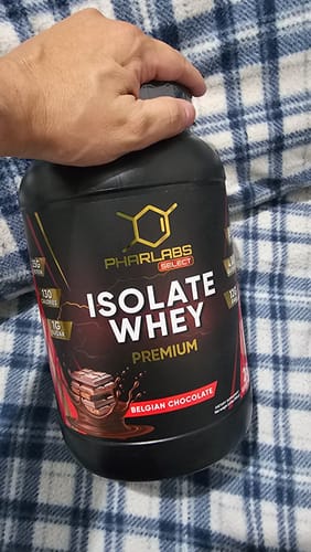 Cliente sosteniendo el envase de Phar Labs Select Isolate Whey Premium sabor Chocolate Belga sobre una manta.