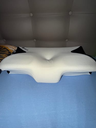 Le coussin d'alignement cervical Cellsius d'un client, de forme ergonomique, posé sur un lit.