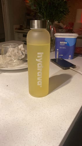 Customer's frosted hydrava bottle filled with the yellow electrolyte drink on a counter.