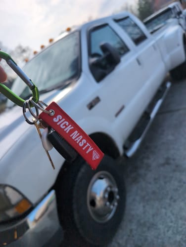Customer holding the red SICK NASTY KEYTAG on a carabiner in front of their white Ford F350 truck.