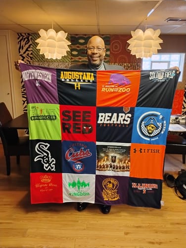 A customer proudly displays their large, colorful Premium T Shirt Quilt made from various shirts.