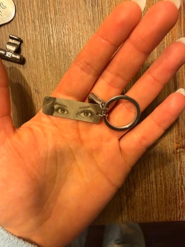 Eine Kundin hält den hochwertigen, gravierten Augen-Schlüsselanhänger in der Handfläche.