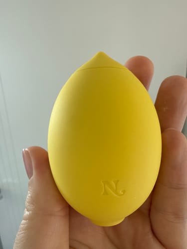 Reviewer holding the yellow, lemon-shaped Lem Clitoral Massager in their hand.