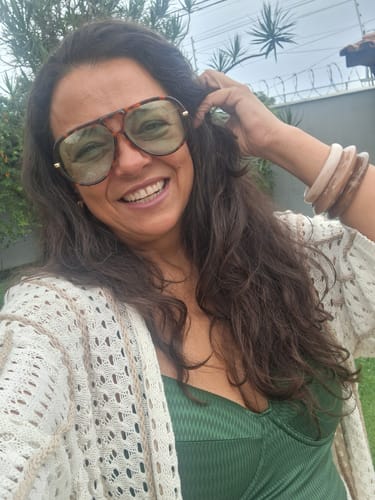 Cliente sorrindo ao ar livre, usando os Óculos Tropea com armação tartaruga e lentes verdes.