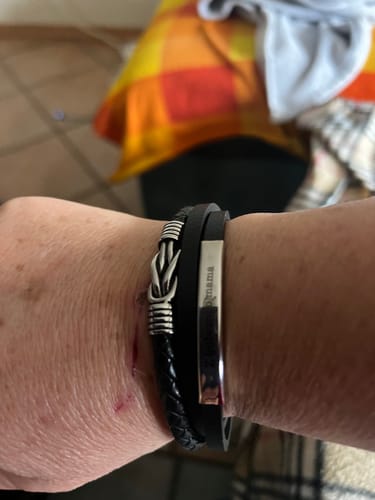 Customer's wrist wearing the black Bond bracelet, showing the silver knot and engraved bar.