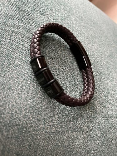 Customer's braided leather Olaf bracelet with black beads, shown resting on a textured fabric.