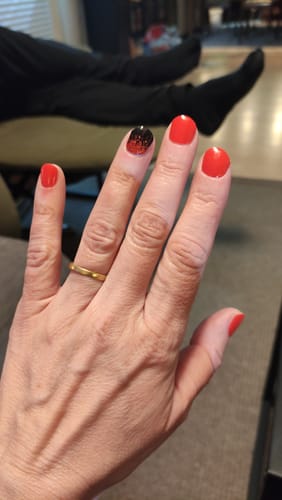 Die Hand einer Kundin mit den aufgetragenen UV-Gel-Nagelfolien 'Hot Date' in einem leuchtenden Rot.