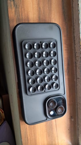 Reviewer's black StickyPod with its suction cups shown attached to the back of a smartphone case.