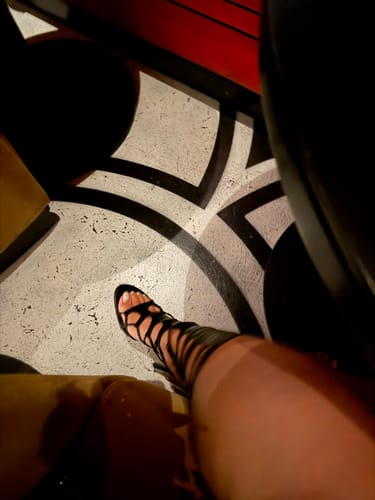 Customer's foot in the black lace-up Snake Heel against a bold black-and-white patterned floor.