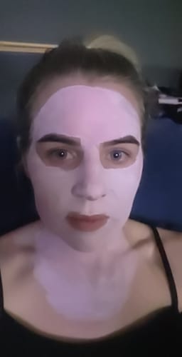 Reviewer with a light pink mask from the Strawberry + Collagen Mask Set applied to their face and neck.
