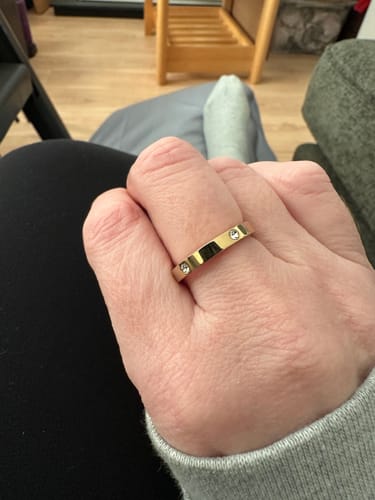 Reviewer's hand showing the gold Eternity Stacking Ring with small inset stones in a casual setting.