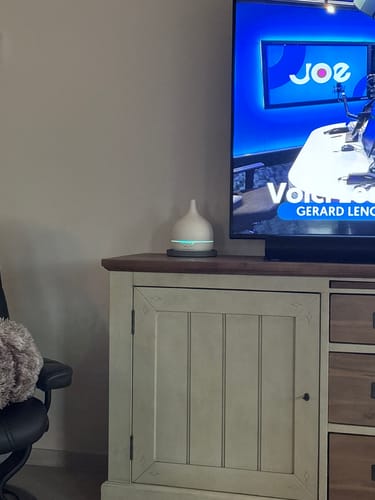 Recensents Close 2 Nature 3.0 aroma diffuser staat verlicht op een dressoir in een woonkamer.