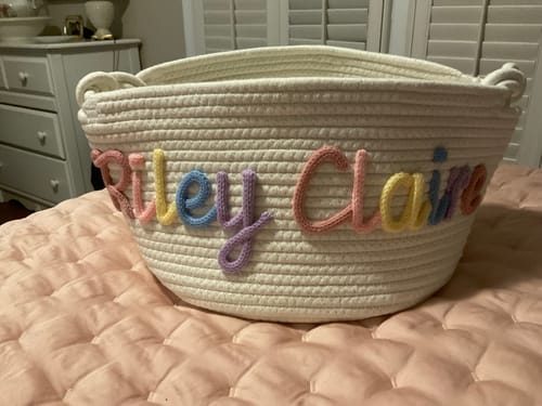 Customer's personalized woven basket showing the name 'Riley Claire' written in multicolor knitted yarn.
