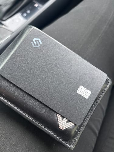 Customer's black SPOTMINDERS Tracking Card PRO shown partially inserted into a black leather wallet.