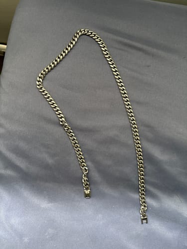 La Cadena Cuban Link de 8mm plateada de un cliente sobre una superficie gris.