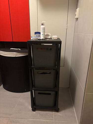 Klant toont de antraciet Rotho Brisen ladekast op wieltjes in een badkamer.