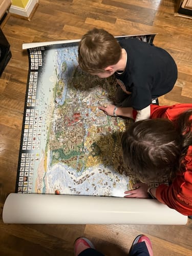 Reviewer's two children examining the large, colorful World's Greatest Search & Discover poster on the floor.