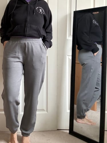 Reviewer showing a front view of the grey Parker Sweatpants, with a side profile visible in a mirror.