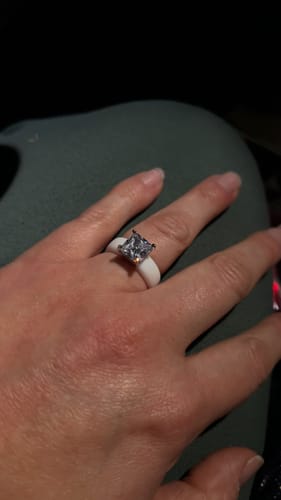 Close-up of a customer's hand wearing the white Silicone Ring with its large princess-cut CZ stone.