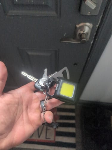 Customer holding the mini flashlight keychain attached to a set of keys.