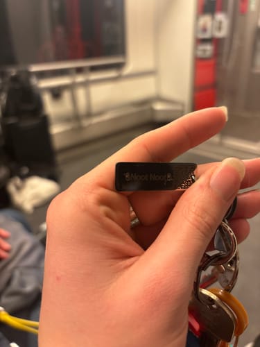 Kunde hält einen schwarzen Schlüsselanhänger mit der Rückseitengravur „Noot Noot“ in der Hand.