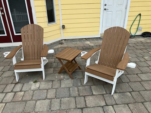 Customer's two two-tone Folding Adirondack Chairs with a small table on a stone patio.