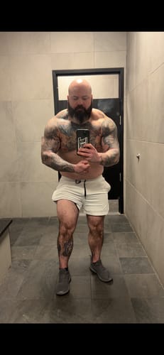 Reviewer flexing in a mirror selfie, showing their muscular and tattooed physique after taking the supplement.