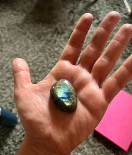 Customer holding a beautiful, iridescent crystal stone from their monthly subscription in their hand.