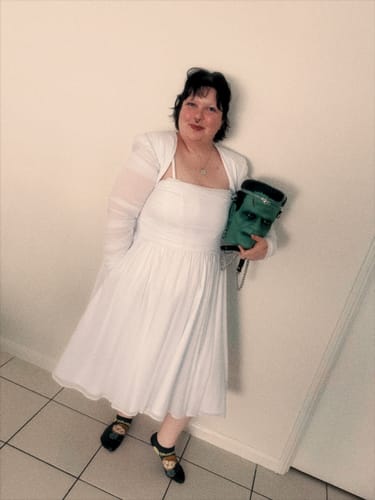Reviewer wearing the white Bride of Frankenstein Swing Dress with a matching bolero, holding a themed purse.