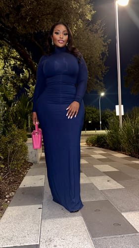 Customer posing outdoors in the blue Butter Turtleneck Maxi Dress at night.