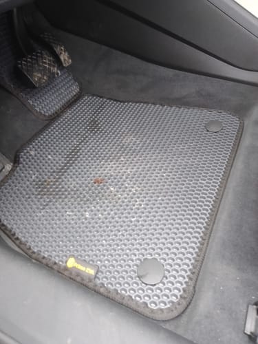 Ciemnoszary dywanik samochodowy klienta po stronie kierowcy, który nie pokrywa w pełni podłogi.