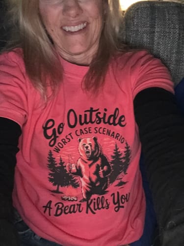 Close-up of a reviewer smiling in the pink Haven't Been Everywhere T-shirt with a humorous bear graphic.