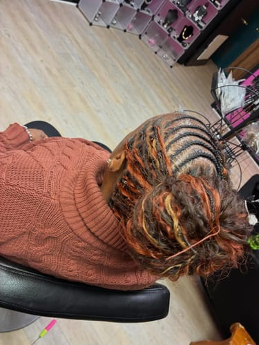 Customer's human hair styled in cornrows and a bun, showing off the mixed orange and blonde colors.