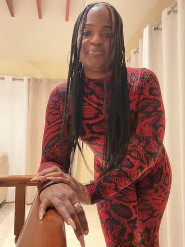 Reviewer posing in the form-fitting Naked Print Jumpsuit in a red and black snakeskin print.