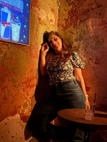 לקוחה לובשת את ג'ינס The Sky - Straight Leg הכחולים בחדר עם תאורה חמימה.