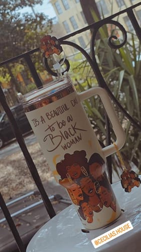 Customer's 'Crème Brûlée' insulated tumbler on a patio table, showing its artwork and custom straw topper.