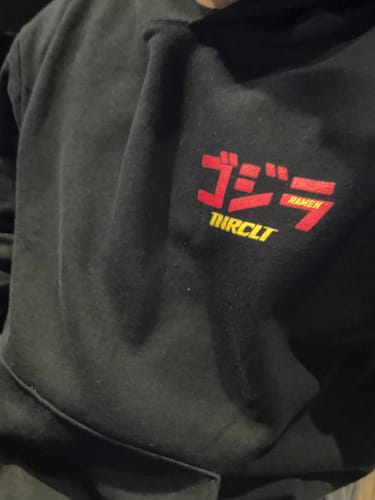 Reviewer's close-up of the black RAMEN MONSTER HOODIE, showing the red and yellow chest graphic.