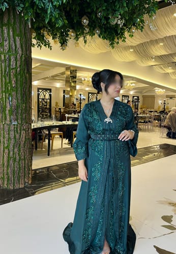 Reviewer standing indoors wearing the elegant Elowen Green dress, showing its full length and intricate embroidery.