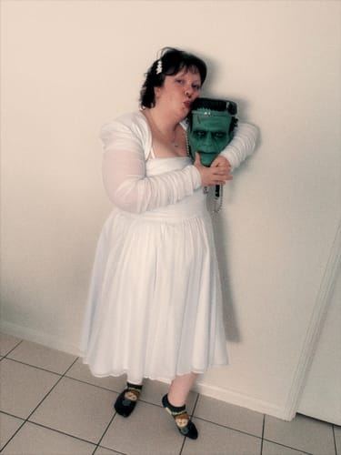 Customer wearing the white Bandage Bolero with its sheer sleeves, holding a Frankenstein mask.