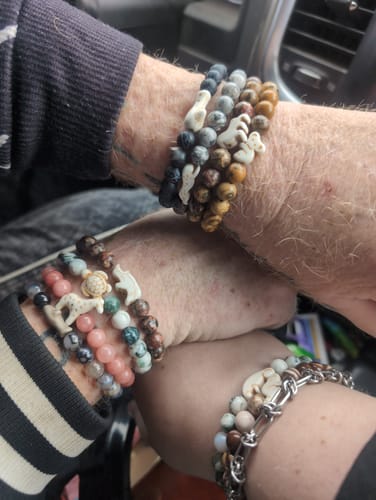 Customer and their family showing their stacked wrists, each wearing multiple colorful, beaded Charge Bracelets.