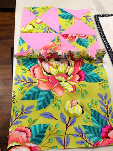 Reviewer joining two colorful quilt blocks for a rag quilt, showing the ruffled seam.