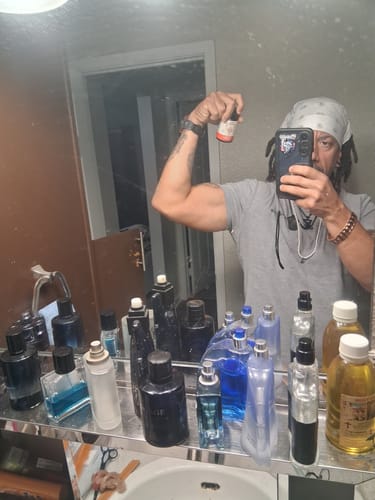 Reviewer taking a mirror photo, flexing their arm while holding a bottle of Primal Reindeer Testosterone Support.