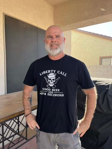 Reviewer smiling while wearing the black Liberty Call - Pour Decisions t-shirt outdoors.