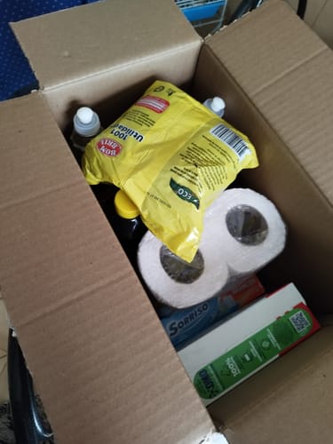Cliente mostrando a Cesta Kit Limpeza Plus dentro de uma caixa de papelão aberta.
