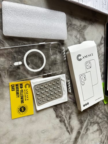 Customer's transparent Anti Yellow Magsafe case for iPhone 15 Plus laid out with its box, warranty card, and an accessory.