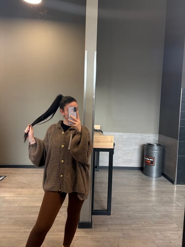 Kundin in einem Spiegelselfie mit dem weichen, braunen Oversized-Cardigan 'CozyGlam' und goldenen Knöpfen.