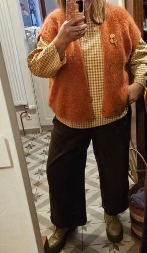 Une cliente portant la Blouse Naomie vichy ocre. La photo montre la blouse ample portée sous un gilet.